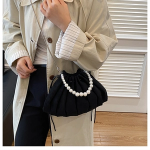 Detail of black pleated cloud bag featuring large white pearls and a drawstring closure