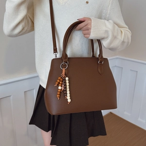 Brown lychee leather tote bag with vintage bead charm accessory shown in a lifestyle setting