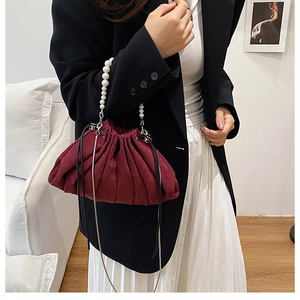 Close-up of burgundy pleated cloud bag with pearl bead handle and fine metal chain strap