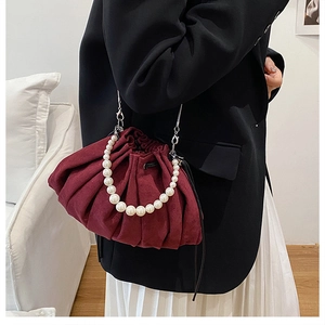 Close-up of deep wine red pleated pouch bag with elegant pearl handle and metal chain