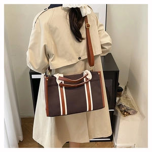 Detail of vintage canvas tote bag with brown leather handles and adjustable strap