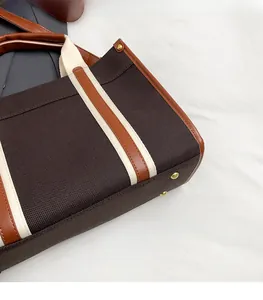 Detail of large canvas tote with leather trim and gold-tone protective bottom studs