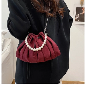 Detail of burgundy pleated pouch bag with large white pearls and silver metal chain strap