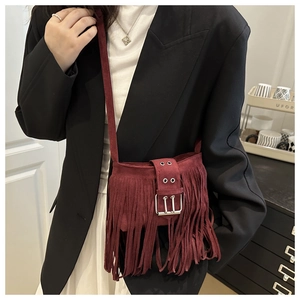 Détail du sac seau en daim bordeaux avec de longues franges et une grande boucle argentée