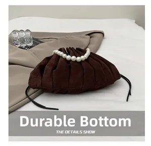 Close-up of pleated suede brown handbag featuring pearl handle and durable base