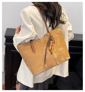 Detail of vintage large-capacity tote bag in tan suede with leather strap and bead charm
