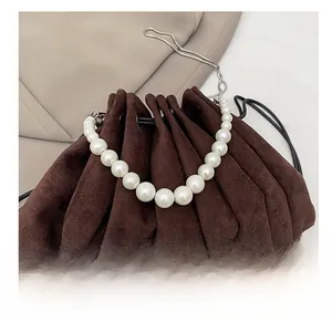 Detail view of dark brown pleated handbag featuring large cream pearls and a silver chain
