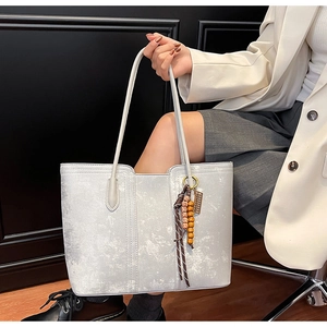 Detailed shot of large grey marble pattern tote bag with vintage beaded charm