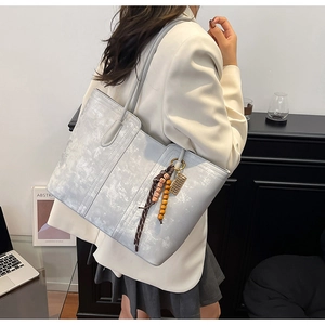Detail of grey textured tote bag with vintage beaded tassel shown in an office setting