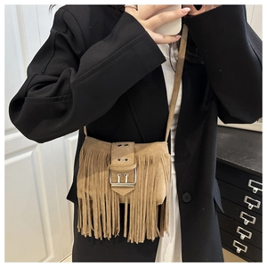 Detail of bohemian fringe crossbody bag in brown suede with silver metal buckle closure
