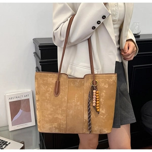 Close-up of vintage brown tote bag with leather handles and decorative tassel detail