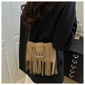 Detail of brown suede crossbody bag featuring dense fringe and silver buckle on model