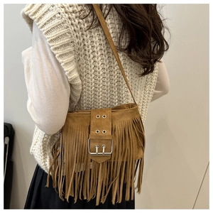 Close-up of brown suede crossbody bag with fringe tassels and metallic buckle detail