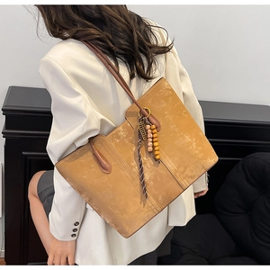 Brown suede tote bag detail with long shoulder straps and ethnic style bead charm decoration