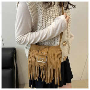 Detalle de bolso de ante marrón con flecos bohemios y hebilla metálica plateada chic