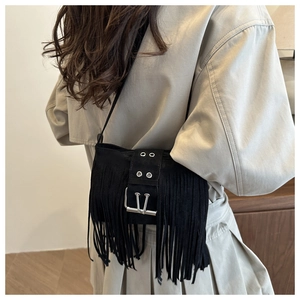 Gros plan d'un sac à bandoulière noir à franges avec boucle en métal et glands bohèmes
