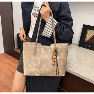 Detail of grey suede tote bag with brown straps and ethnic beaded wood charm detail