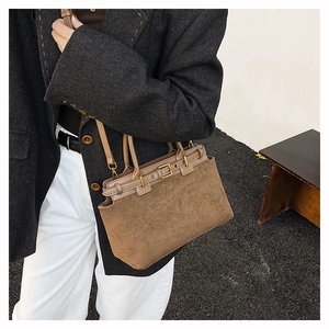 Close-up of brown faux suede handbag texture with leather strap and buckle details