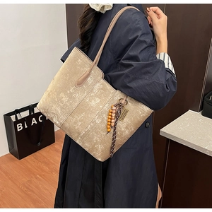 Detail of champagne gold tote bag featuring beaded bohemian tassel and marble texture