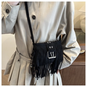 Detail of black matte suede crossbody bag featuring dense bohemian fringe and metal buckle
