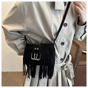 Détail du sac seau noir en daim avec franges et bandoulière à œillets métalliques