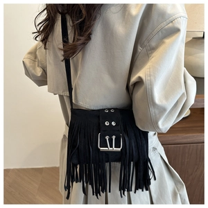 Detail of bohemian black suede crossbody bag with long tassels and buckle on a model