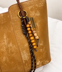 Detailed close-up of brown leather handbag featuring a vintage wooden bead and abacus charm
