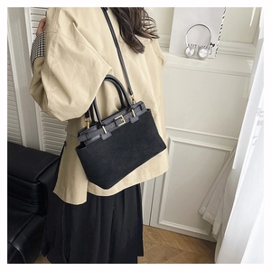 Detail of vintage black tote bag with gold buckle and matte leather texture shown on person