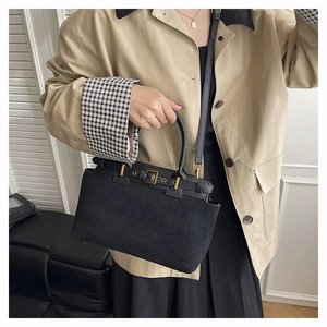 Detail of vintage black suede handbag featuring elegant gold buckle and top handle design