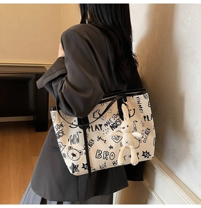 Close-up of cream graffiti tote bag with plush bunny charm and large capacity design