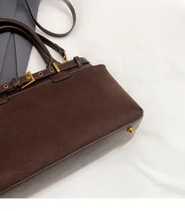 Detail of dark brown tote featuring suede patchwork and gold metal buckle hardware