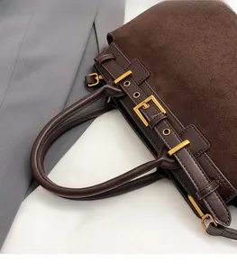 Detail of dark brown vintage tote bag showing suede texture and golden metal buckle