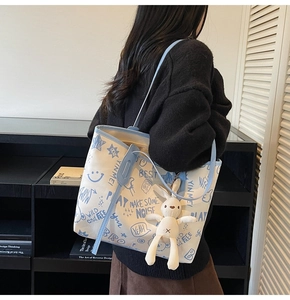 Détail du sac cabas en toile graffiti avec pendentif lapin et bordure en similicuir bleu