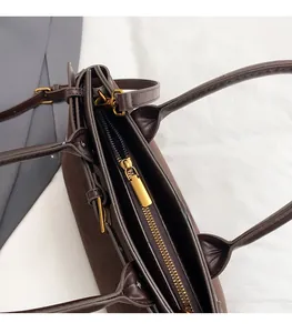 Detailed close-up of premium gold zipper and suede texture on dark brown tote bag