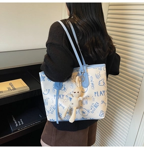 Détail du cabas blanc avec imprimé graffiti dessin animé bleu et pendentif lapin mignon