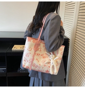 Détail du sac cabas en toile blanche avec motifs graffiti rouges et pendentif lapin