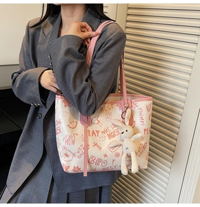 Detail of white graffiti tote bag with pink straps and a cute plush rabbit charm