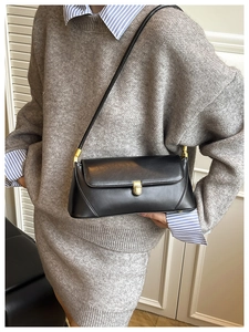 Détail d'un sac baguette en cuir noir avec boucle dorée et fine bandoulière élégante