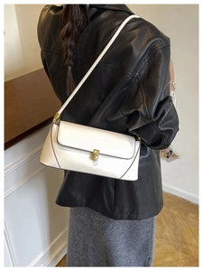 Détail du sac baguette blanc avec fermoir rotatif doré et bandoulière minimaliste