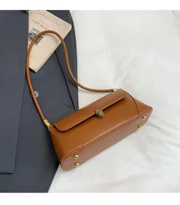 Détail du sac baguette en cuir caramel avec boucle en bronze et rivets de protection de fond