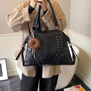 Fashionable black tote bag with silver studs and a donut charm for stylish commuting