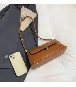 Détail d'un sac baguette vintage marron avec boucle dorée et comparaison de taille