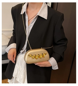 Close-up of gold wave-embossed acrylic clutch bag with delicate metallic chain strap