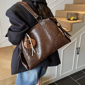 Deep brown studded tote bag with donut charm shown from a stylish back view angle