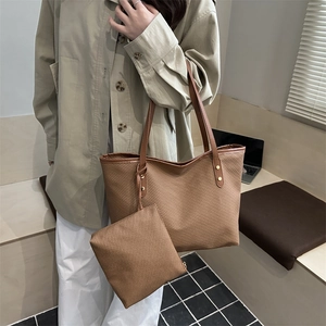 Brown woven tote bag and clutch set with gold rivet details on modern interior background