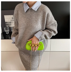 Detail of neon green clutch featuring a wavy gold handle and delicate chain strap