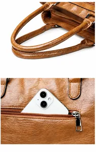 Detail view of the soft top handle and back zipper pocket on the brown leather tote bag