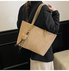 Détail du grand sac cabas kaki mat avec breloque ours porté par un mannequin