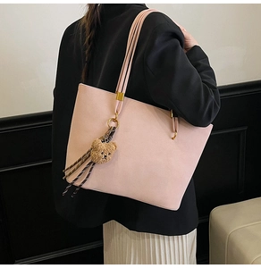 Sac fourre-tout rose mat avec breloque ours et pompon tressé sur la bandoulière de détail
