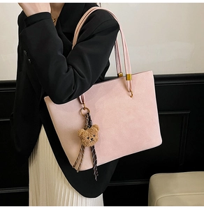Détail du sac cabas rose poudré mat avec breloque ours porté sur une veste noire